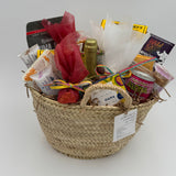 Gift basket with various items including a champagne, snacks, chocolates and nectars on a white background